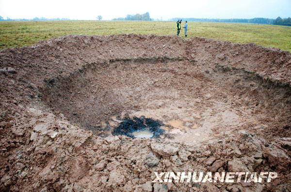 10月26日,在拉脱维亚一个北部城镇,两名警官正在观察一个“疑似”陨石坑。近日,一个“疑似”陨石在拉脱维亚北部一城镇旁坠落,砸出一个直径约为15米的陨石坑。
