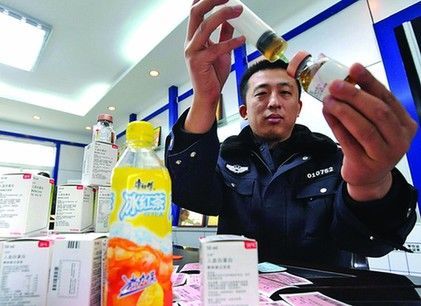 民警演示犯罪嫌疑人造假过程:把冰红茶注射进收购来的真药瓶,就当真药来出售。(记者 左庆 摄)
