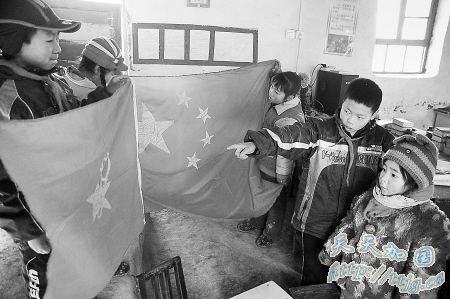 “小老师”王明成(右二)给入学不久的小同学教认国旗和少先队队旗。